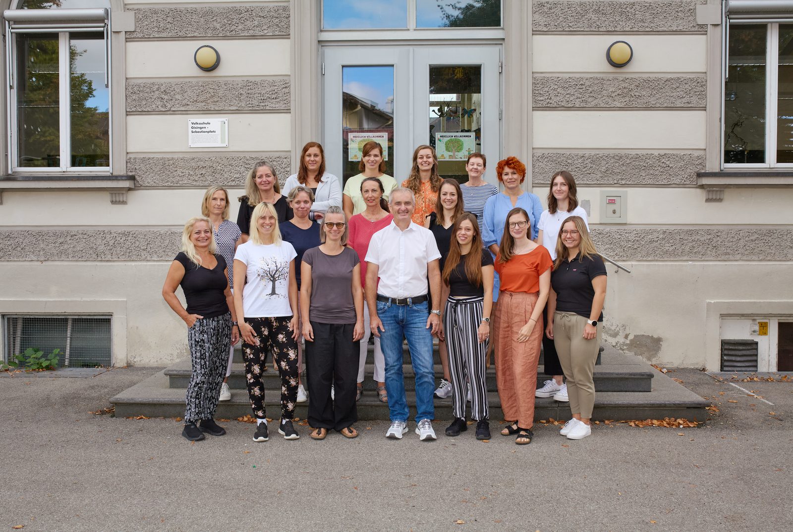 Gruppenfoto des Lehrerinnen- und Lehrerteams vor dem Eingang des Schulgebäudes