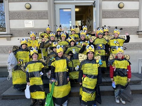 Kinder der Klassen 4a und 4b als Bienen verkleidet als Gruppe vor dem Schulgebäude