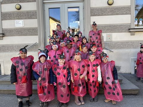 Kinder der Klassen 1a, 1b und 1c als Marienkäfer verkleidet als Gruppe vor dem Schulgebäude